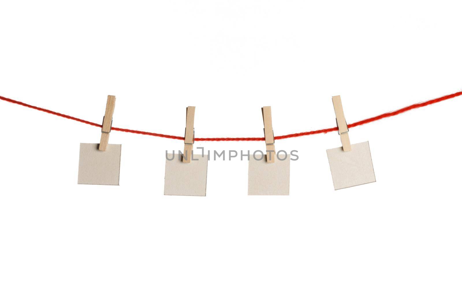Set of four white blank paper notes held on red string with clothespins isolated on white background