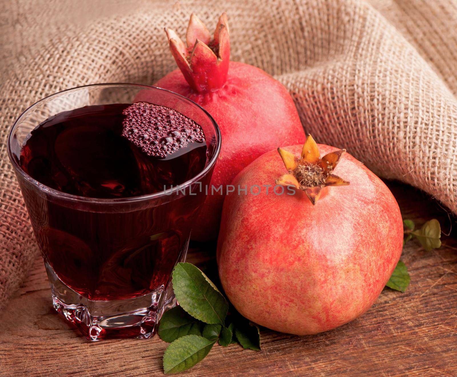 Garnet juice in a glass and pomegranate on wooden boards