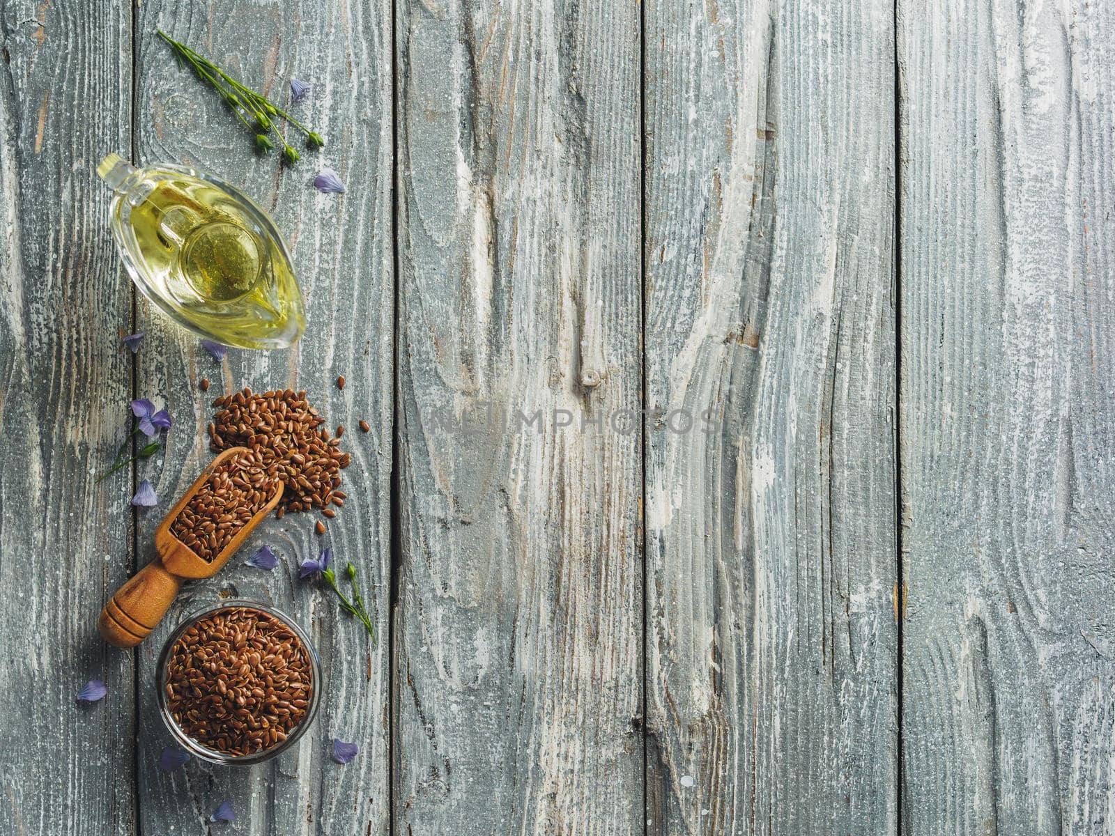 Flax seeds and flax oil. Brown linen seeds and flaxseed oil on old gray wooden background. Copy space. Top view or flat lay.