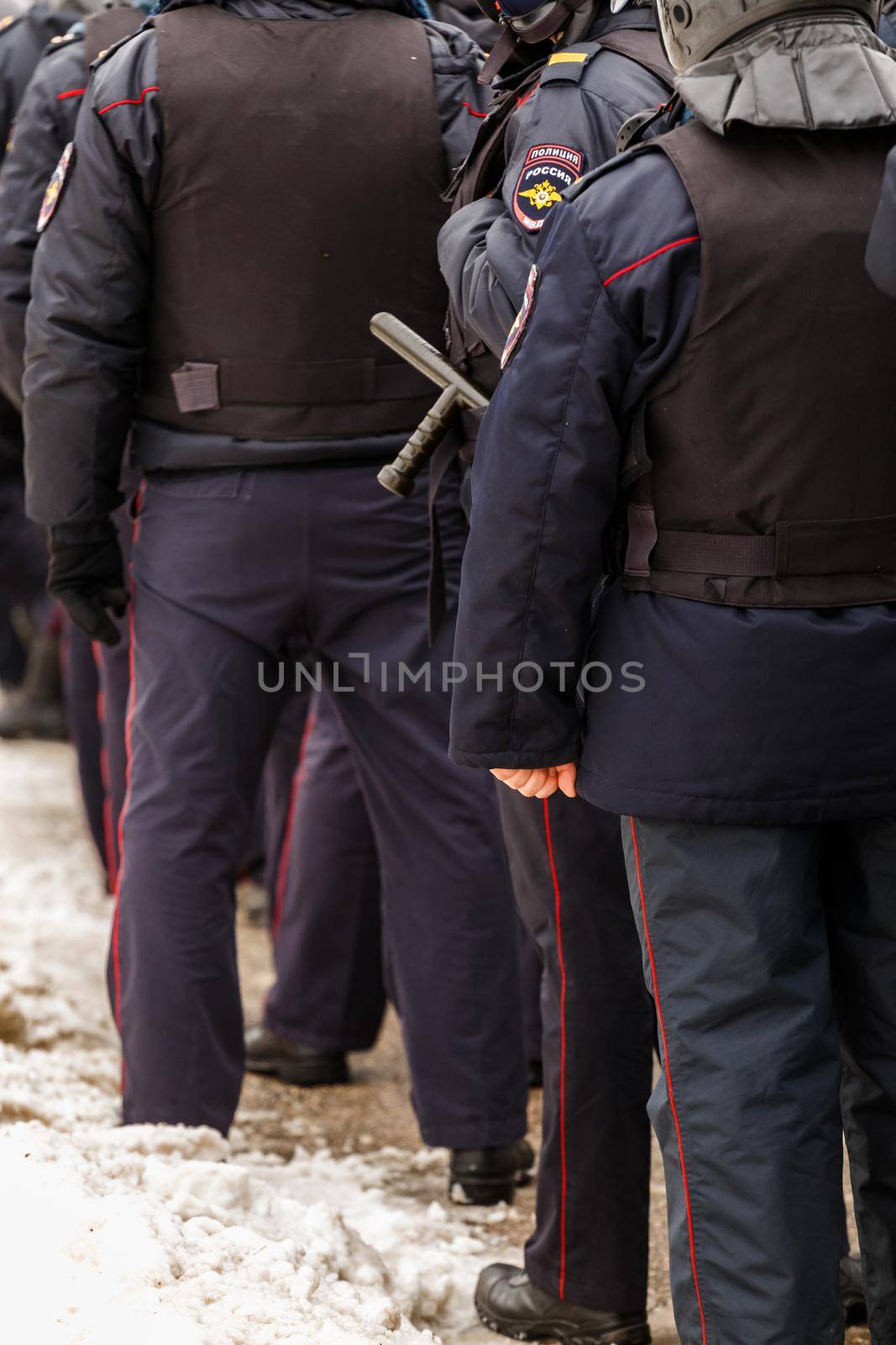 TULA, RUSSIA - JANUARY 23, 2021: Crowd of police officers in black uniform with bulletproof vests and pistols - view from back. by z1b