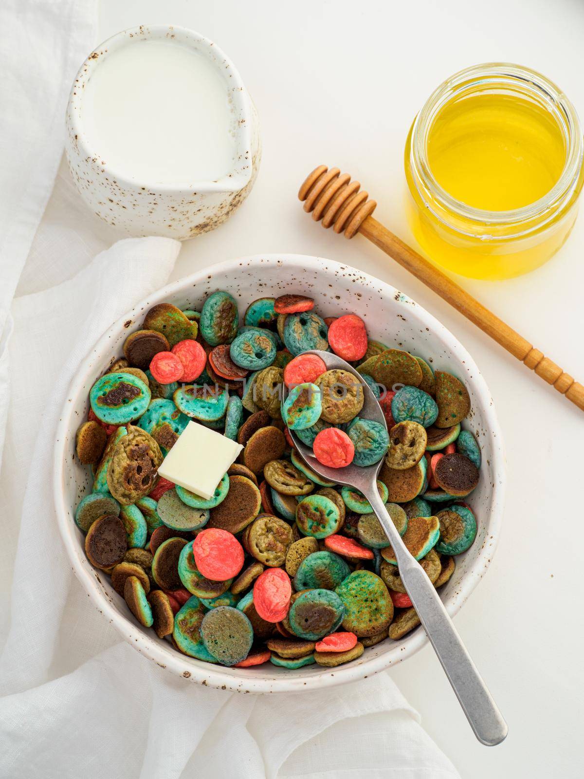 Trendy food - pancake cereal. Heap of colorful mini cereal pancakes. Tiny pancakes with natural color - green matcha, turquose spirulina, blue pea, red fragon fruit