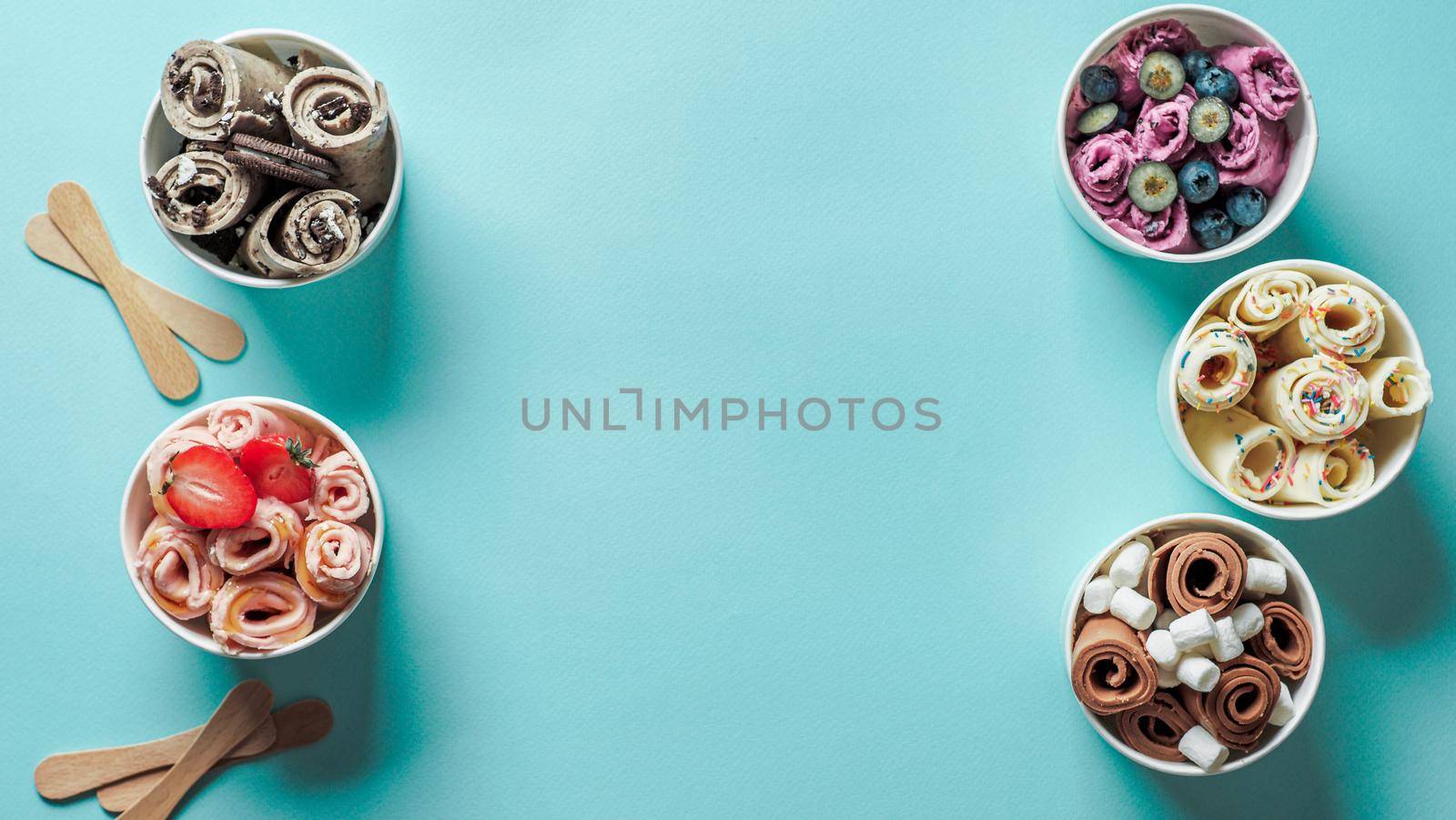 rolled ice creams in cone cups on blue background. Different iced rolls top view or flat lay. Thai style rolled ice cream with copy space in center for text or design. Banner
