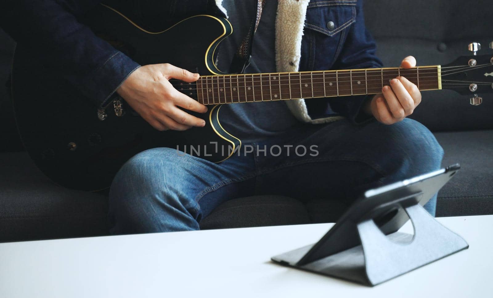 Man learns how to play the guitar. Remote online lesson.