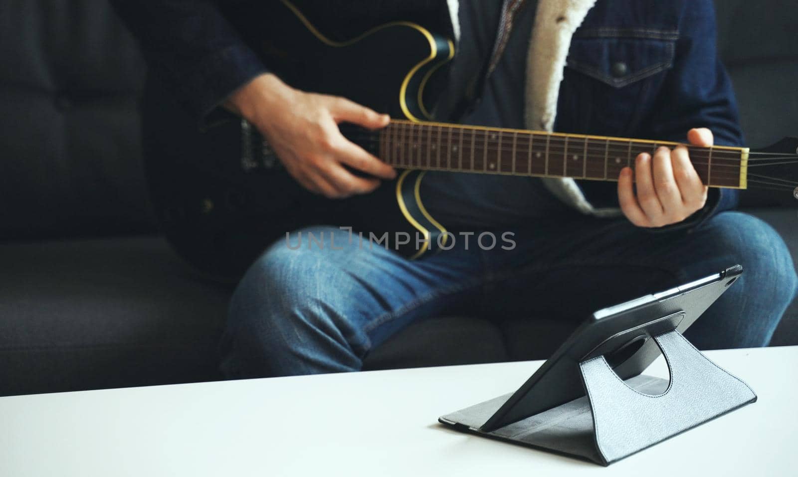 Man learns how to play the guitar. Remote online lesson.