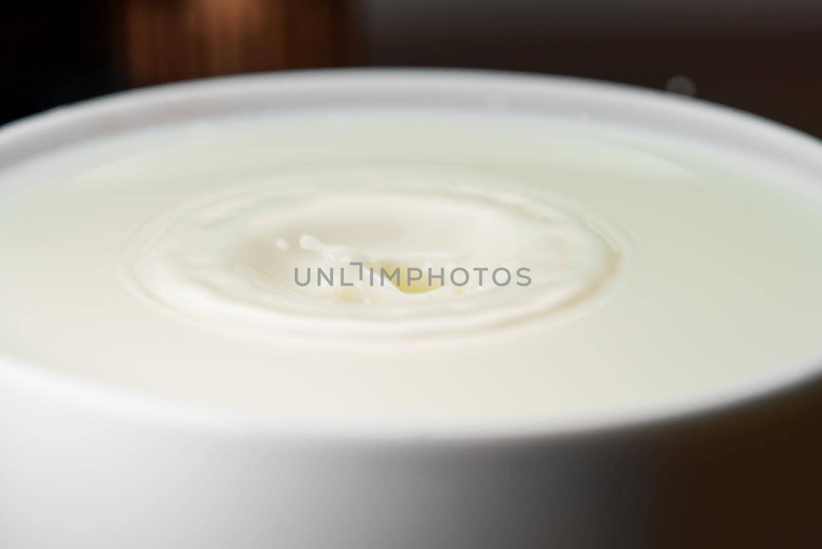 Milk drop falls into the filled cup.