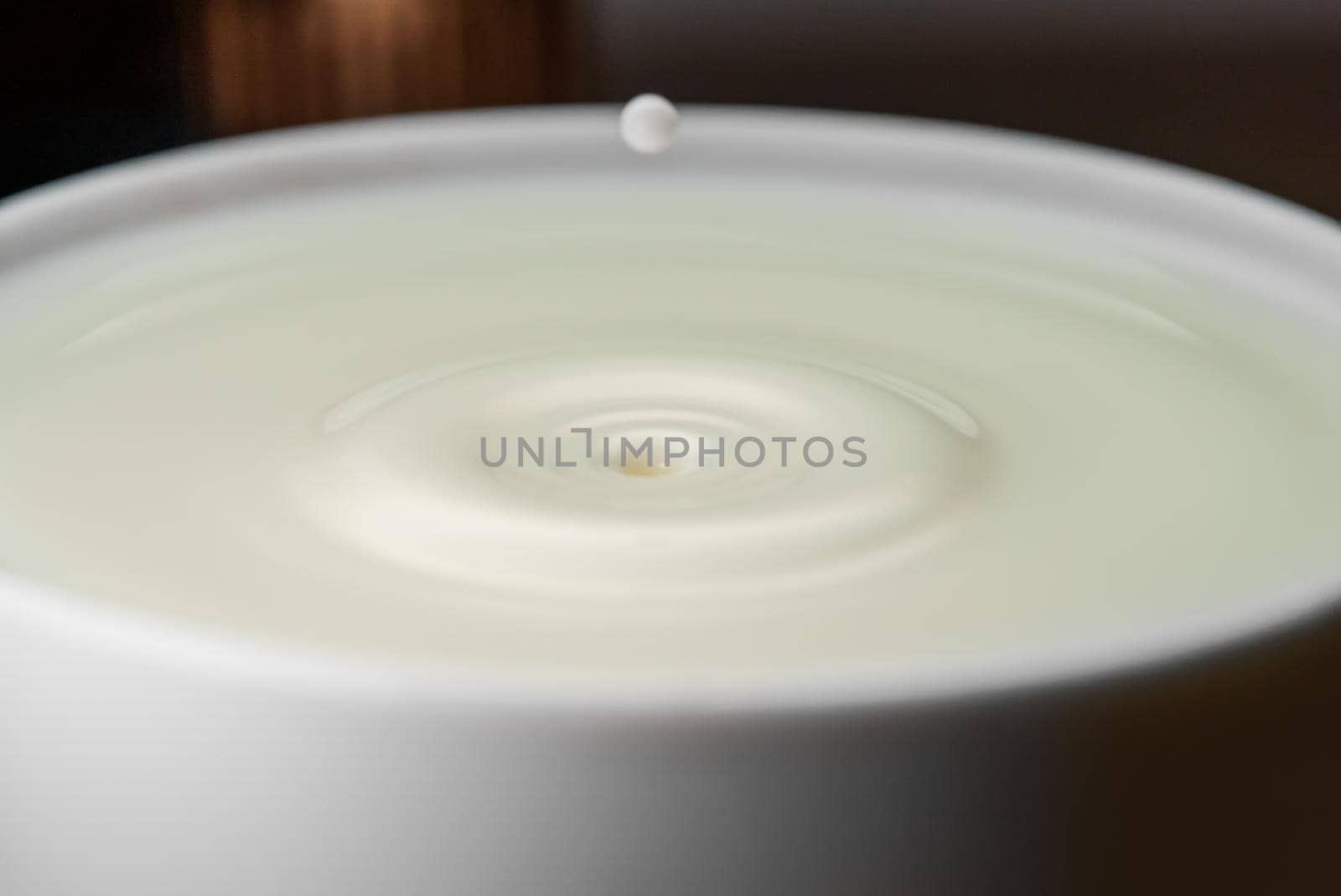 Milk drop falls into the filled cup.