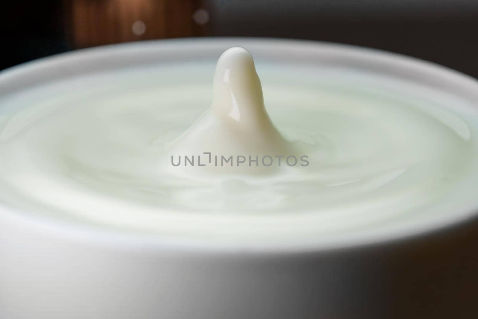 Milk drop falls into the filled cup.