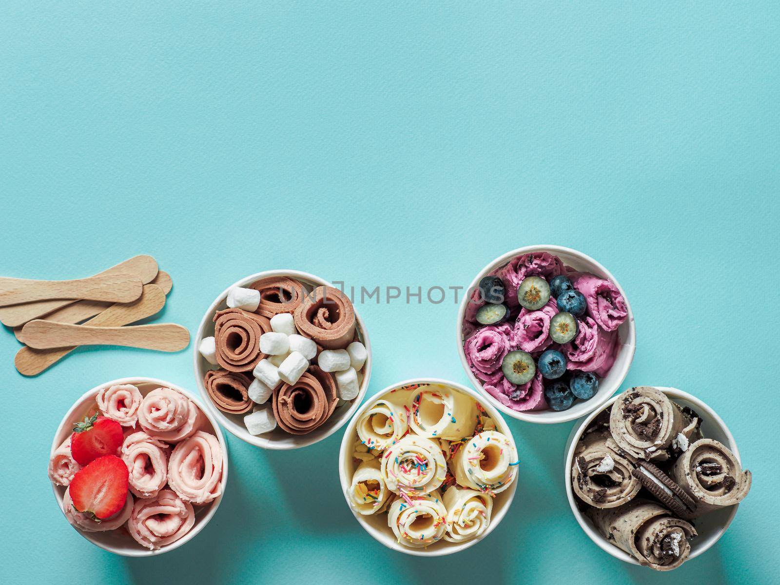 rolled ice creams in cone cups on blue background. Different iced rolls top view or flat lay. Thai style rolled ice cream with copy space for text or design