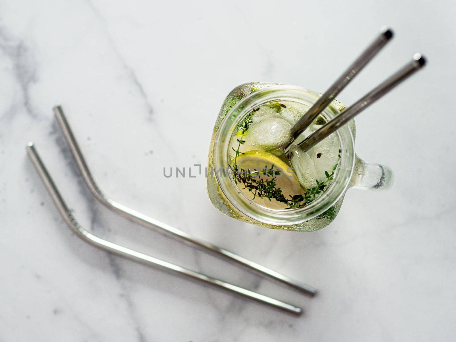 Metal drinking straws and cold drink in glass mason jar on white marble background. Top view or flat lay. Recyclable straws, zero waste concept. Banner.