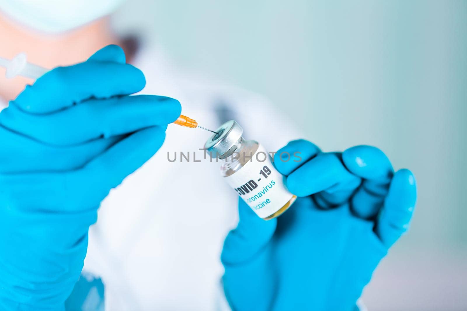 Woman doctor or nurse in uniform and gloves wearing face mask protective in lab holding medicine vial vaccine bottle with COVID-19 Coronovirus vaccine label