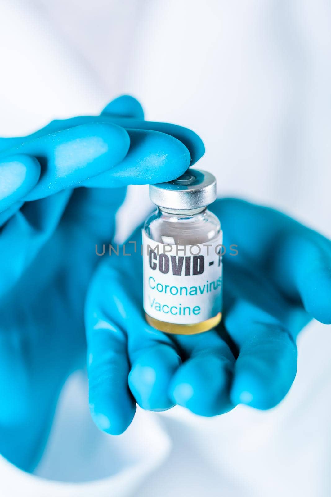 Woman doctor or nurse in uniform and gloves wearing face mask protective in lab holding medicine vial vaccine bottle with COVID-19 Coronovirus vaccine label