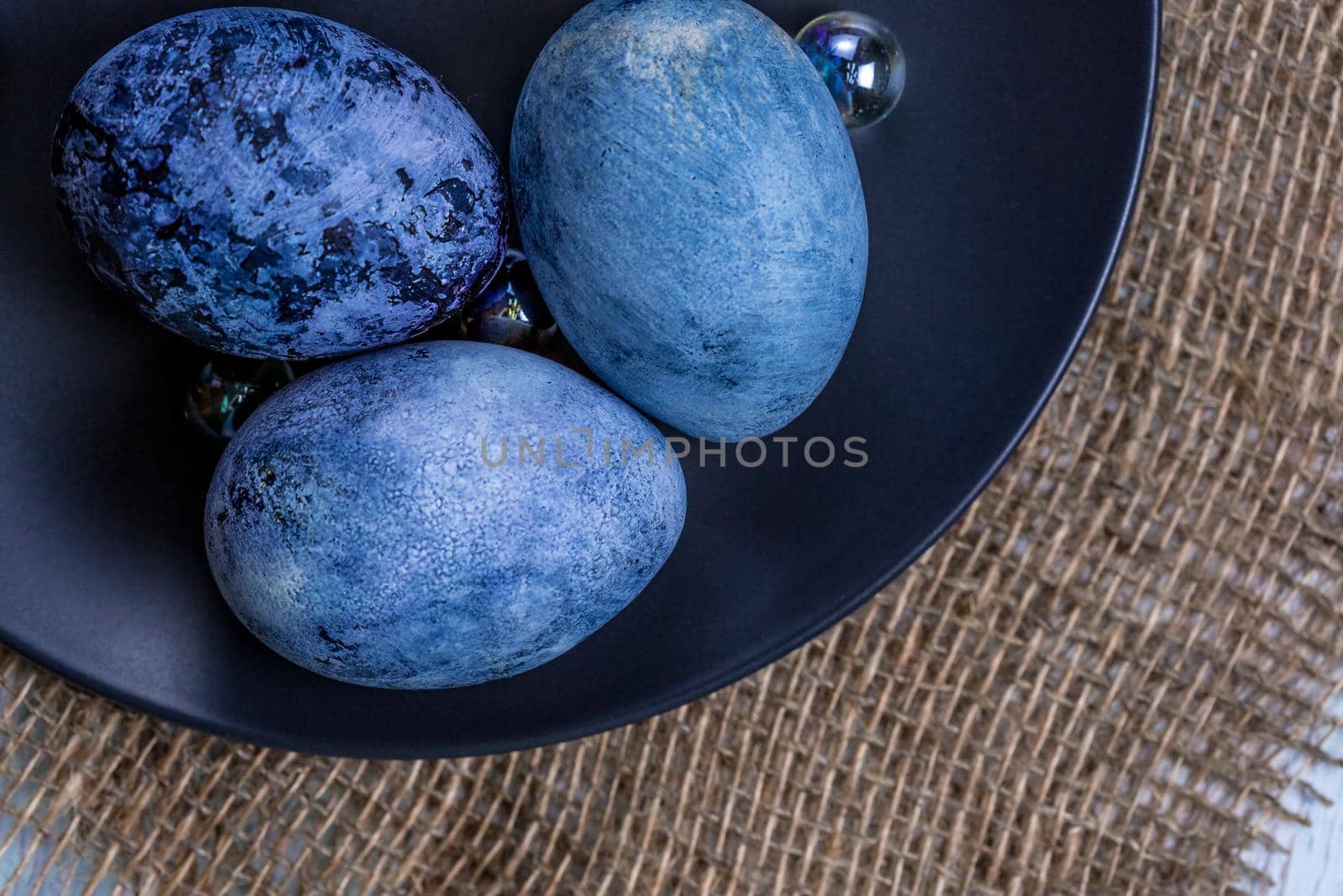 Blue Easter eggs on a dark ceramic plate on burlap on an light wooden background by galinasharapova