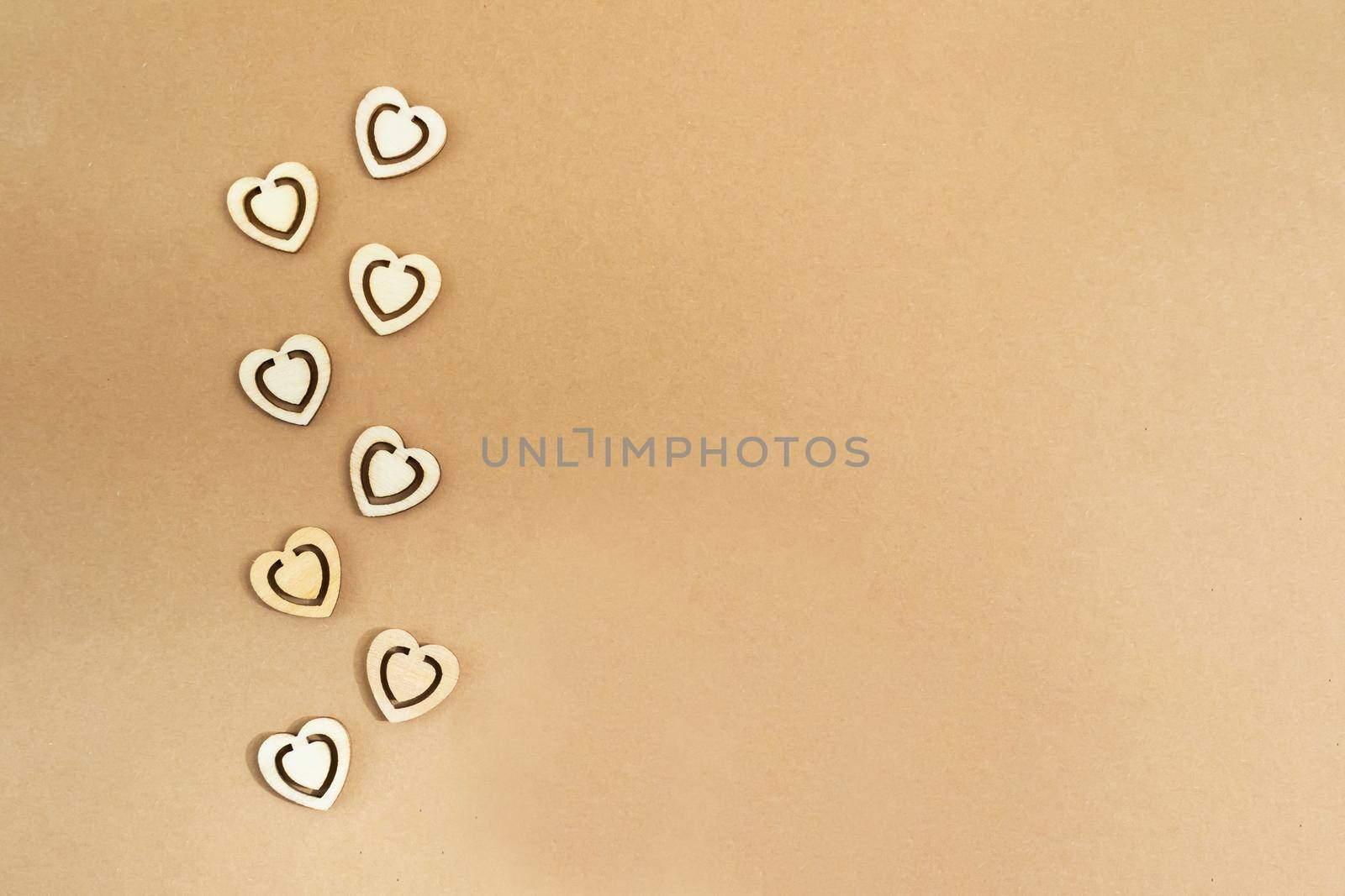 Wooden hearts on a pastel craft paper background. Abstract background with wood cut shapes. Sainte Valentine, mother's day, birthday greeting cards, invitations. Copy space.