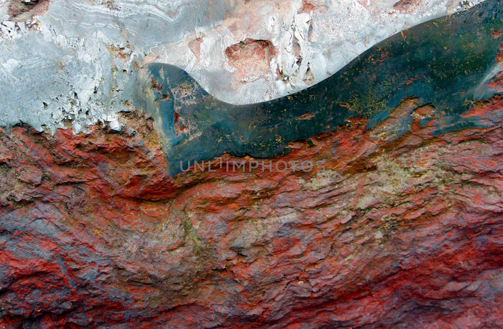Closeup of a red, white and blue rough stone texture background