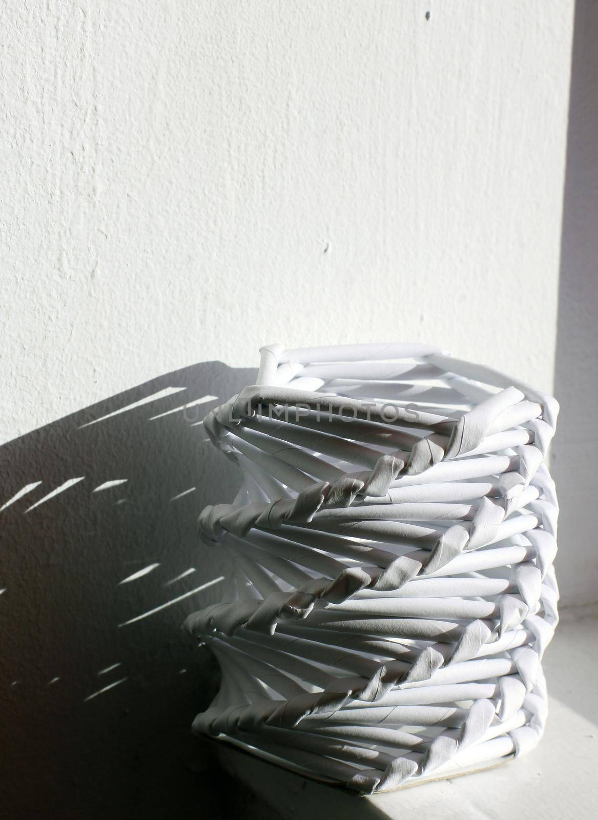 Handmade paper pencil holder and shadow over a white wall