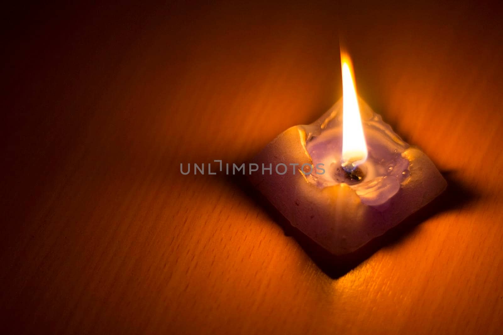 Abstract background with a consumed wax candle burning over a wood background