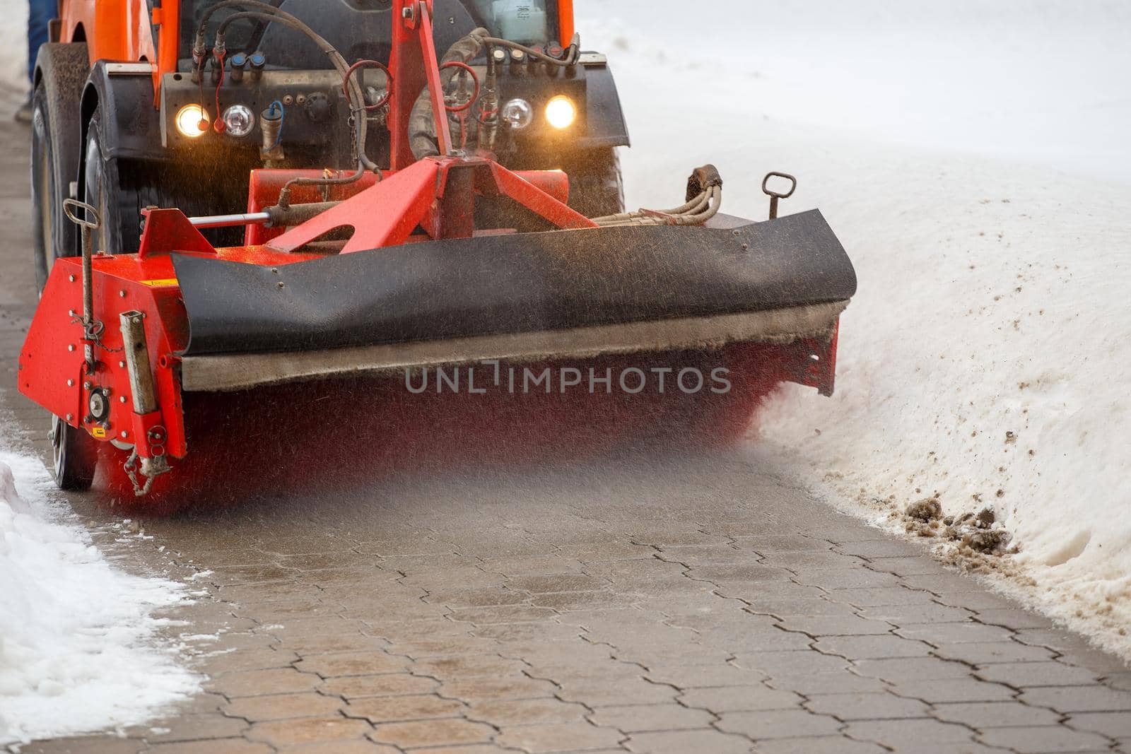 Snow cleaning. Snow removal tractor clearing snow from pavement with special round spinning brush, by z1b