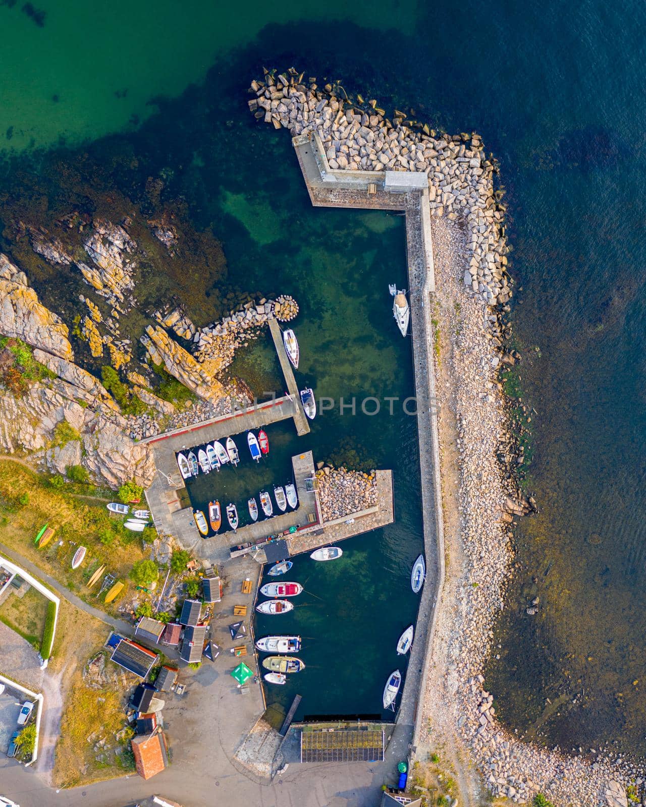 Bornholm, Denmark - August 09, 2020: Top down drone view of anchored boats in the small port of Sandvig