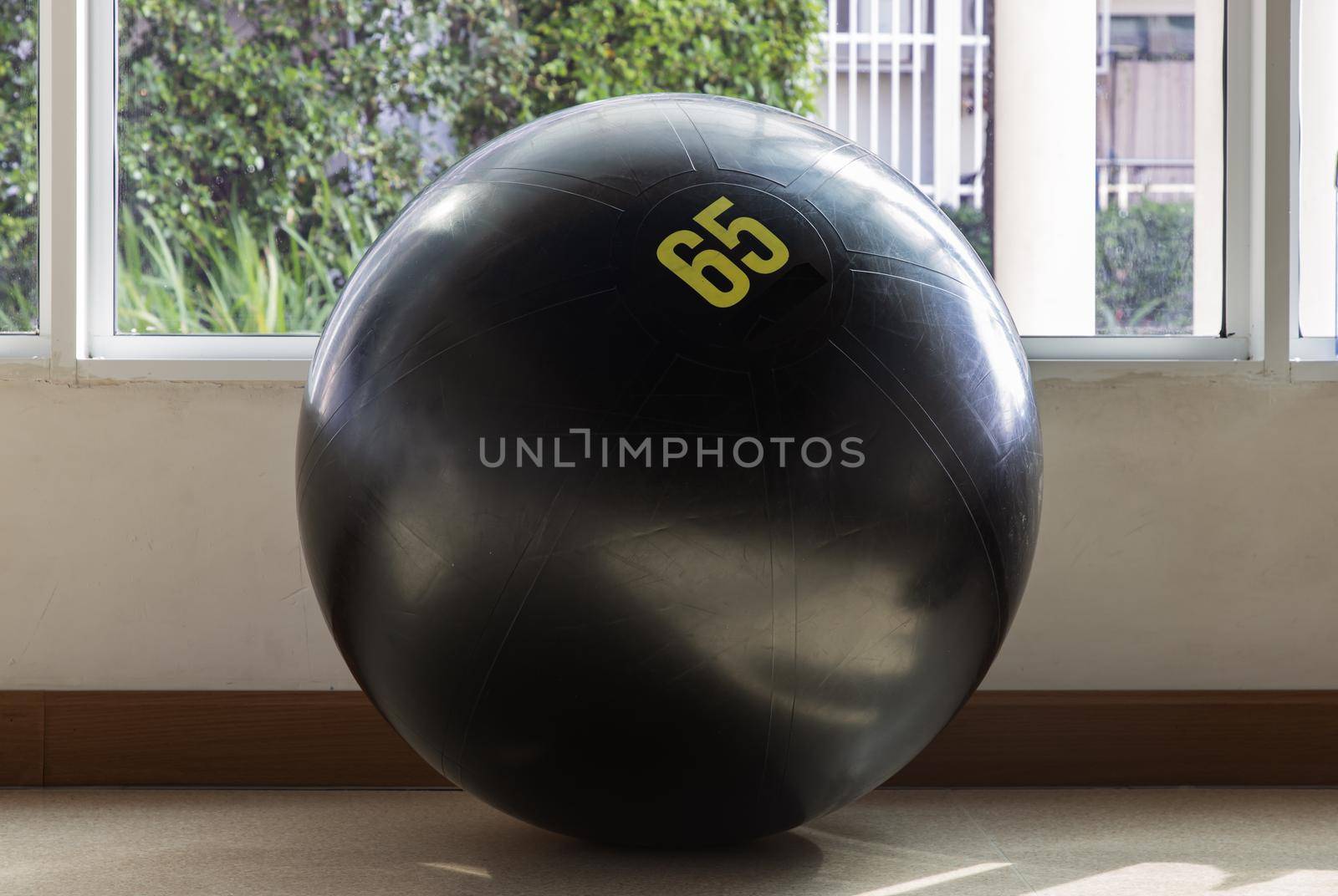 Black fitness exercise ball on the floor gym studio. Equipment for doing sport exercises with free space. Gym concept, Selective focus.