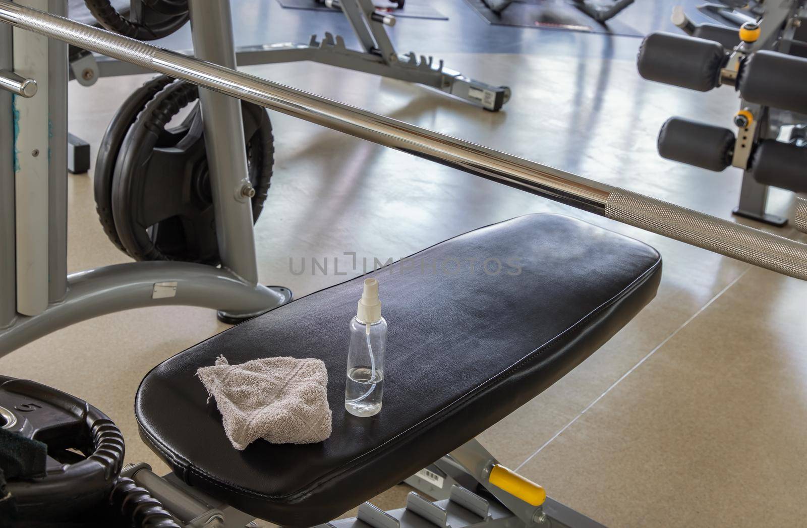 Alcohol sanitizer spray and fabric on exercise machine at gym. Equipment for doing sport exercises, Selective focus.