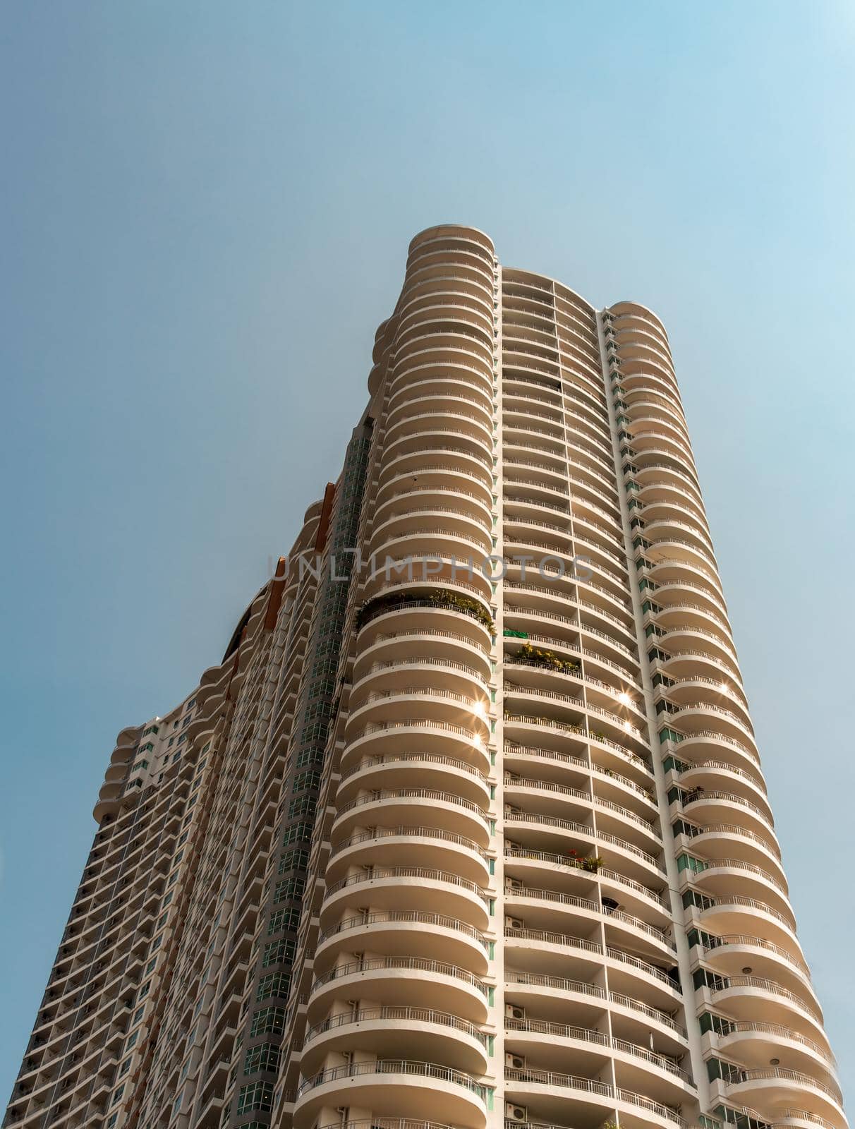 Bangkok, Thailand - 18 Jan 2021 : Low angle looking up at Condominium building with repeating structure and clouds background. Architecture concept. Selective focus.