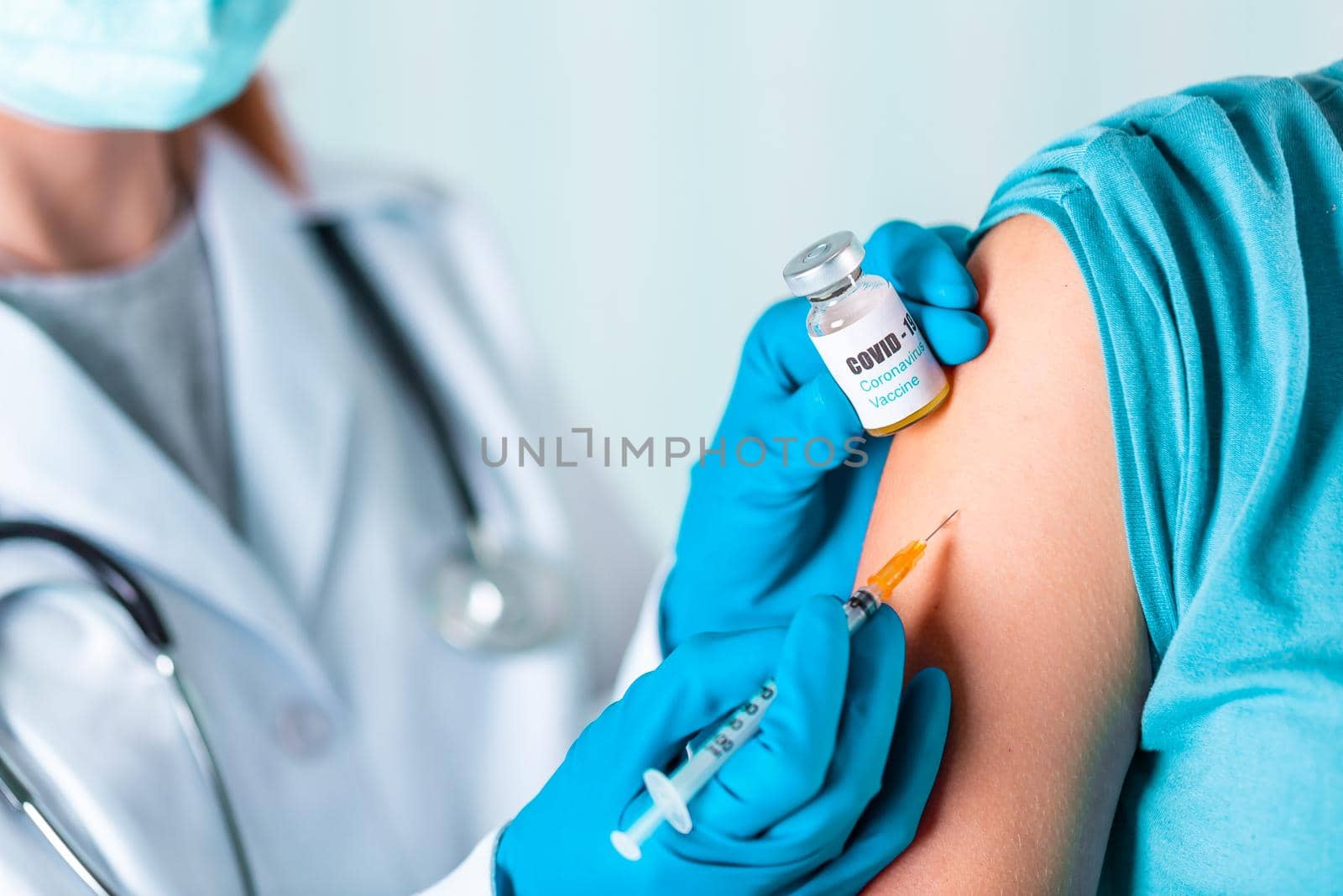 Woman doctor or nurse in uniform and gloves wearing face mask protective in lab, making an injecion holding vaccine bottle with COVID-19 Coronovirus vaccine label