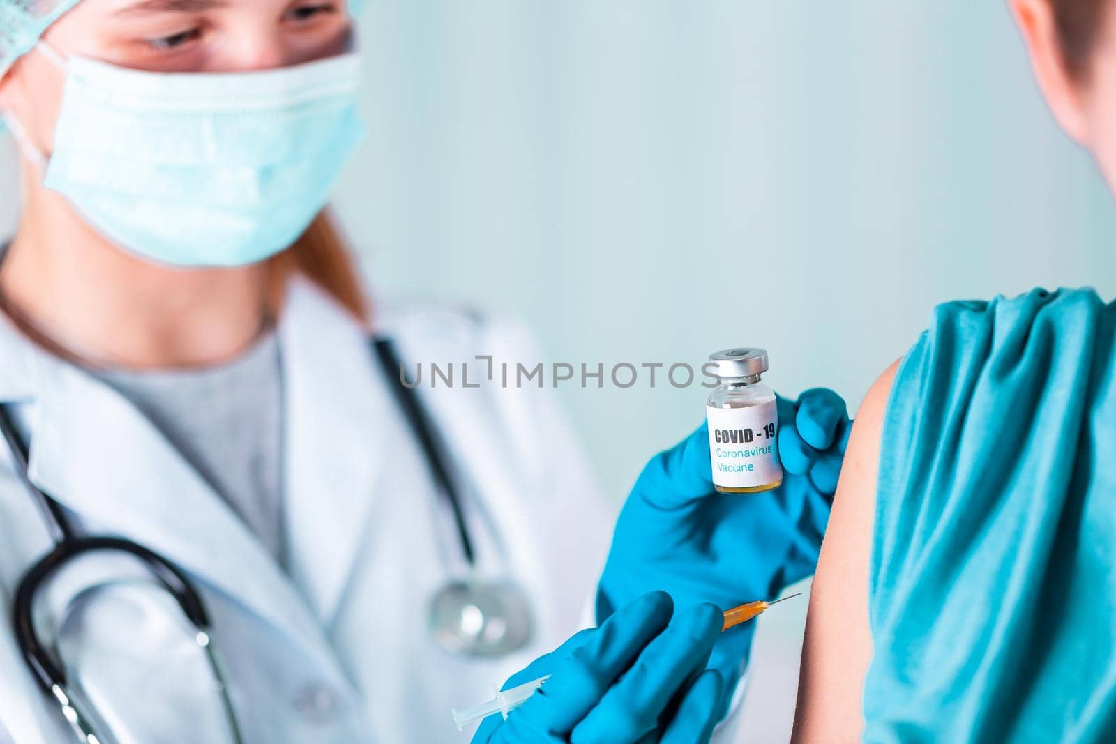 Woman doctor or nurse in uniform and gloves wearing face mask protective in lab, making an injecion holding vaccine bottle with COVID-19 Coronovirus vaccine label