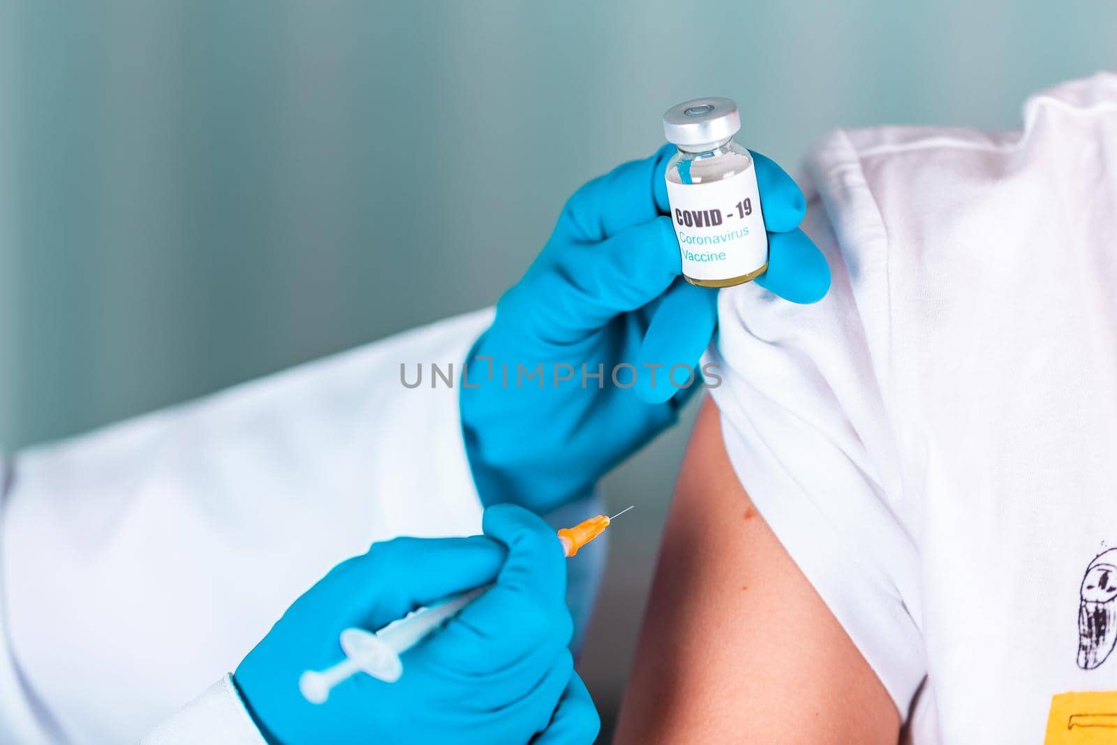 Woman doctor or nurse in uniform and gloves wearing face mask protective in lab, making an injecion holding vaccine bottle with COVID-19 Coronovirus vaccine label