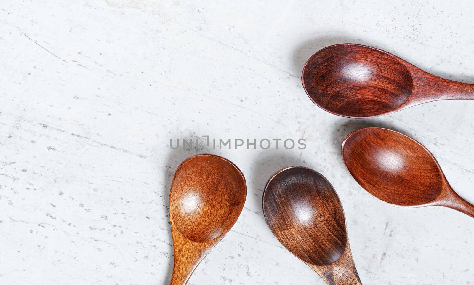 Small spoons made of dark wood, on white working board, view from above, space for text left side.