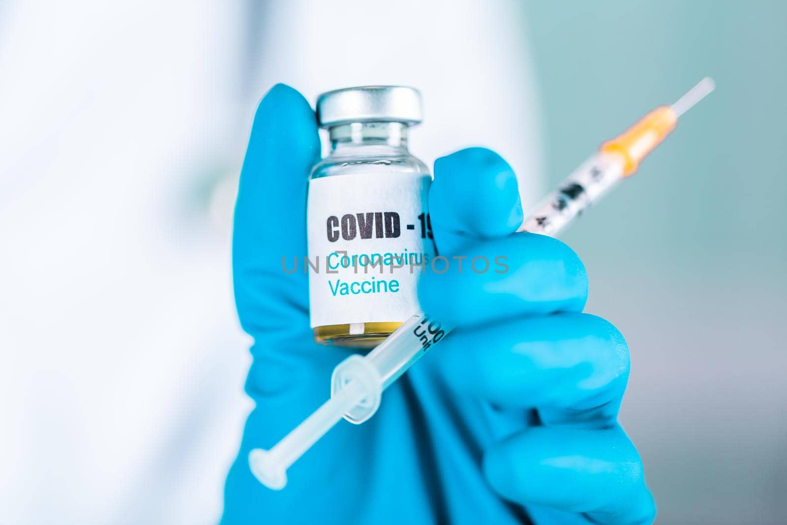 Woman doctor or nurse in uniform and gloves wearing face mask protective in lab, holding medicine vial vaccine bottle with COVID-19 Coronovirus vaccine label