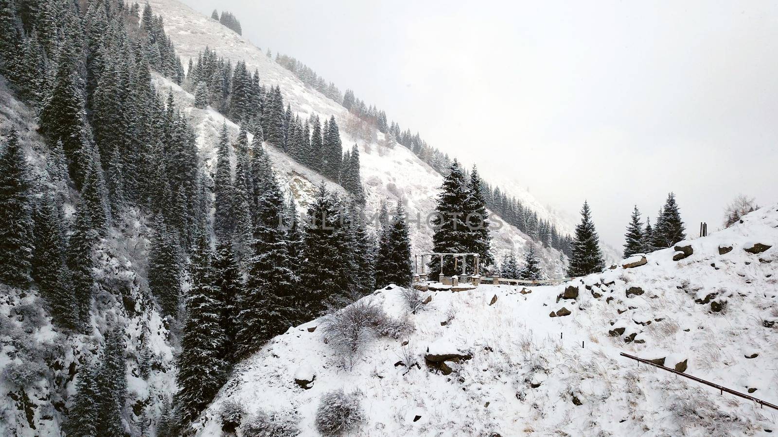 A broken gazebo stands on snowy hill in mountains by Passcal