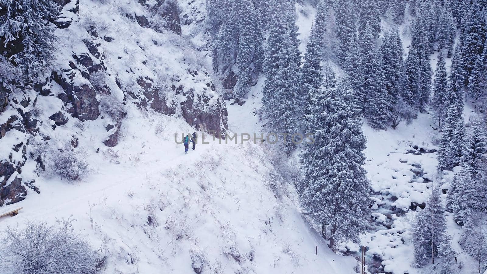 A group of people descend an iron ladder in the mountains. Active family holidays. Fir trees and snow-covered slopes. Top view from the drone. People dressed in costumes of the mountain. Almarasan.