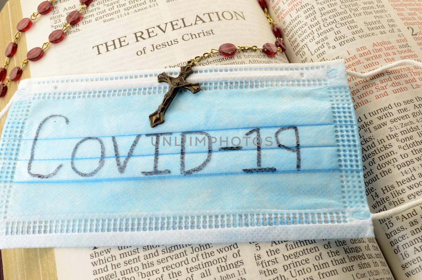 An open Bible and rosary with a mask marked with the pandemic Covid19 as some turn to God for help in trying times.