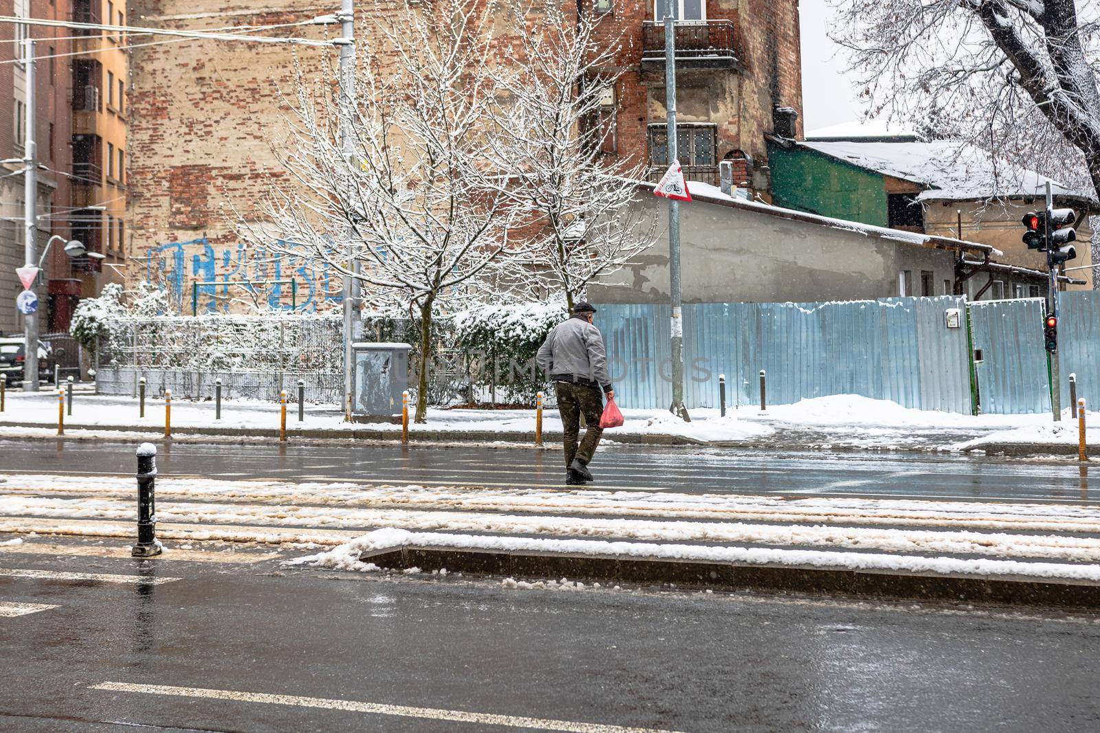 Pedestrian crossing the snowy road, snowy winter day in Bucharest, Romania, 2021