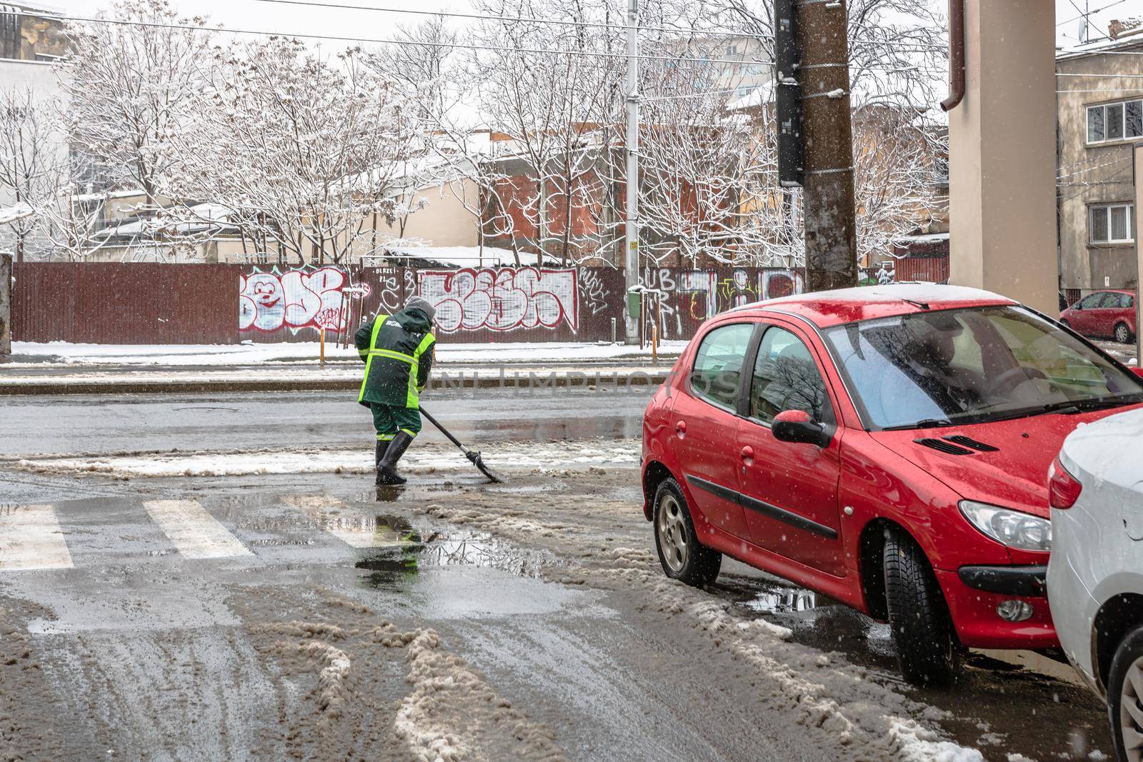 Snow removal, worker cleaning the snowy road in Bucharest, Romania, 2021 by vladispas