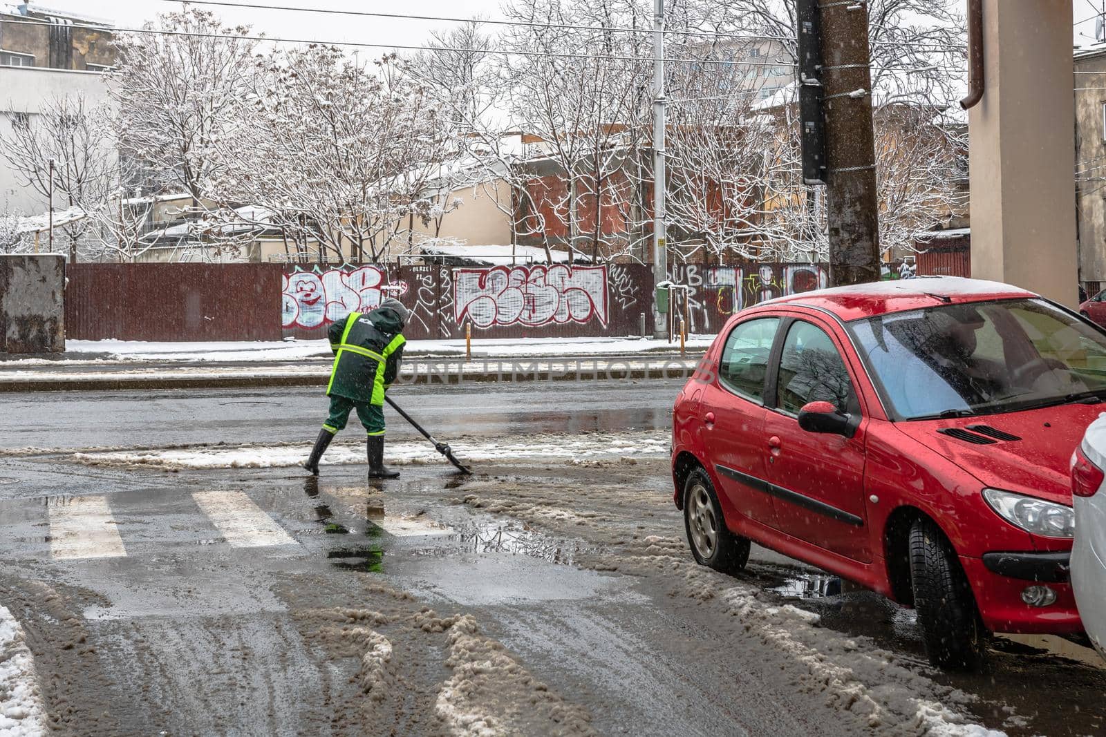 Snow removal, worker cleaning the snowy road in Bucharest, Romania, 2021 by vladispas