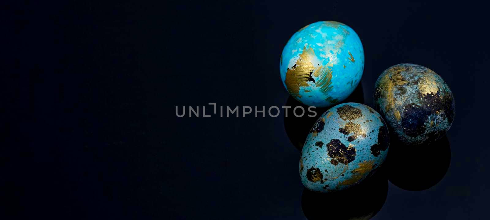 Easter quail eggs painted by hand in blue and gold color on the black surface. by galinasharapova