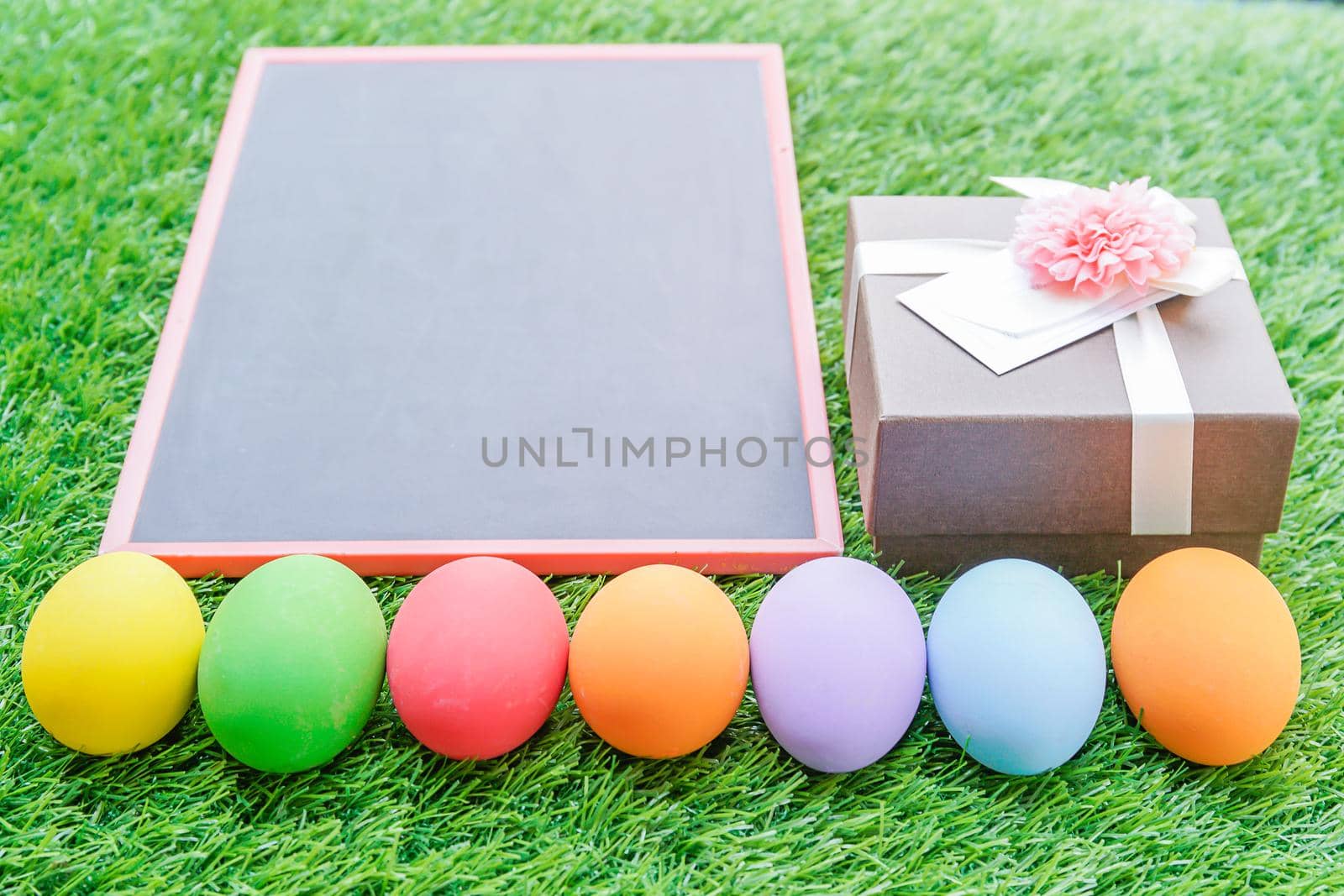 Close up Colorful easter eggs on green grass and blackboard mockup with copy space