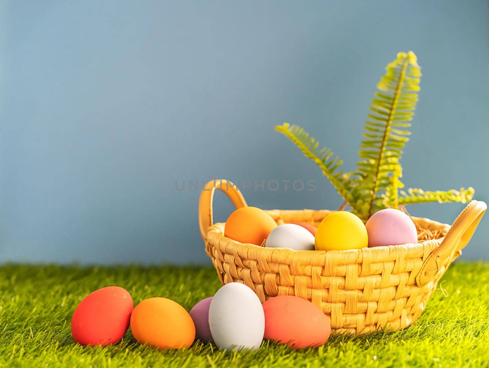 Colorful easter eggs in the basket on green grass background with copy space