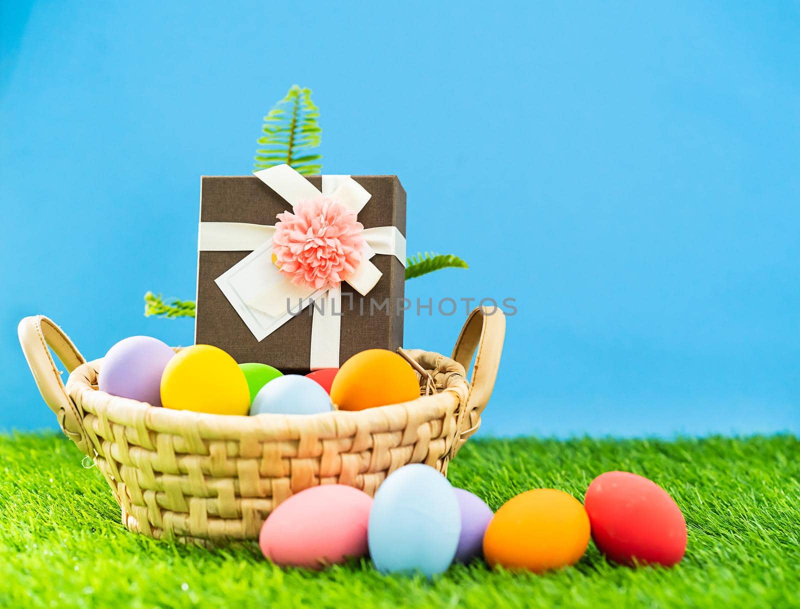 Colorful easter eggs in the basket on green grass background with copy space