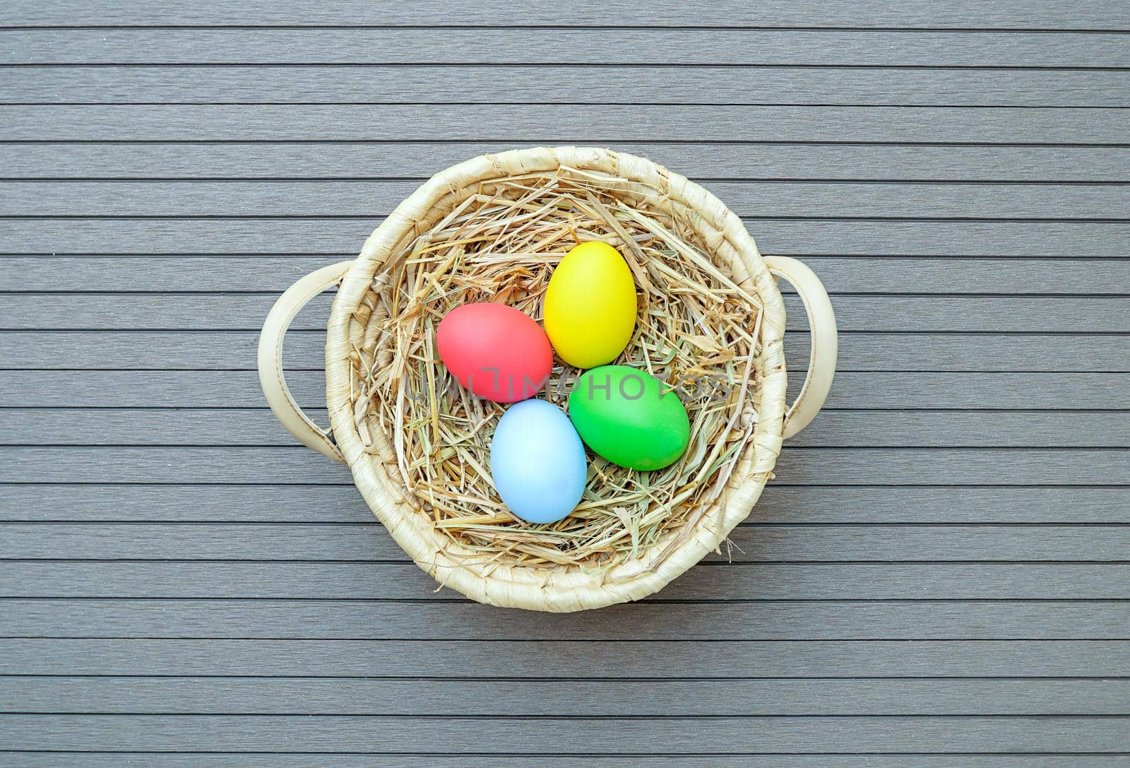 Colorful easter eggs in the basket on wood background with space