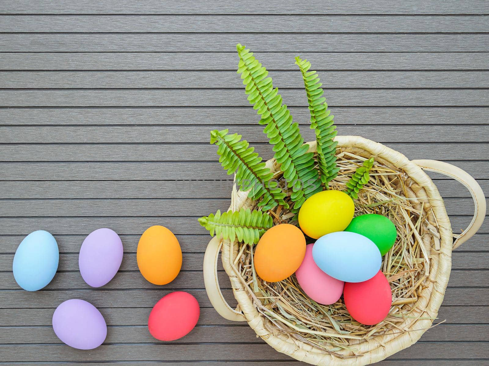 Colorful easter eggs in the basket on wood background with space