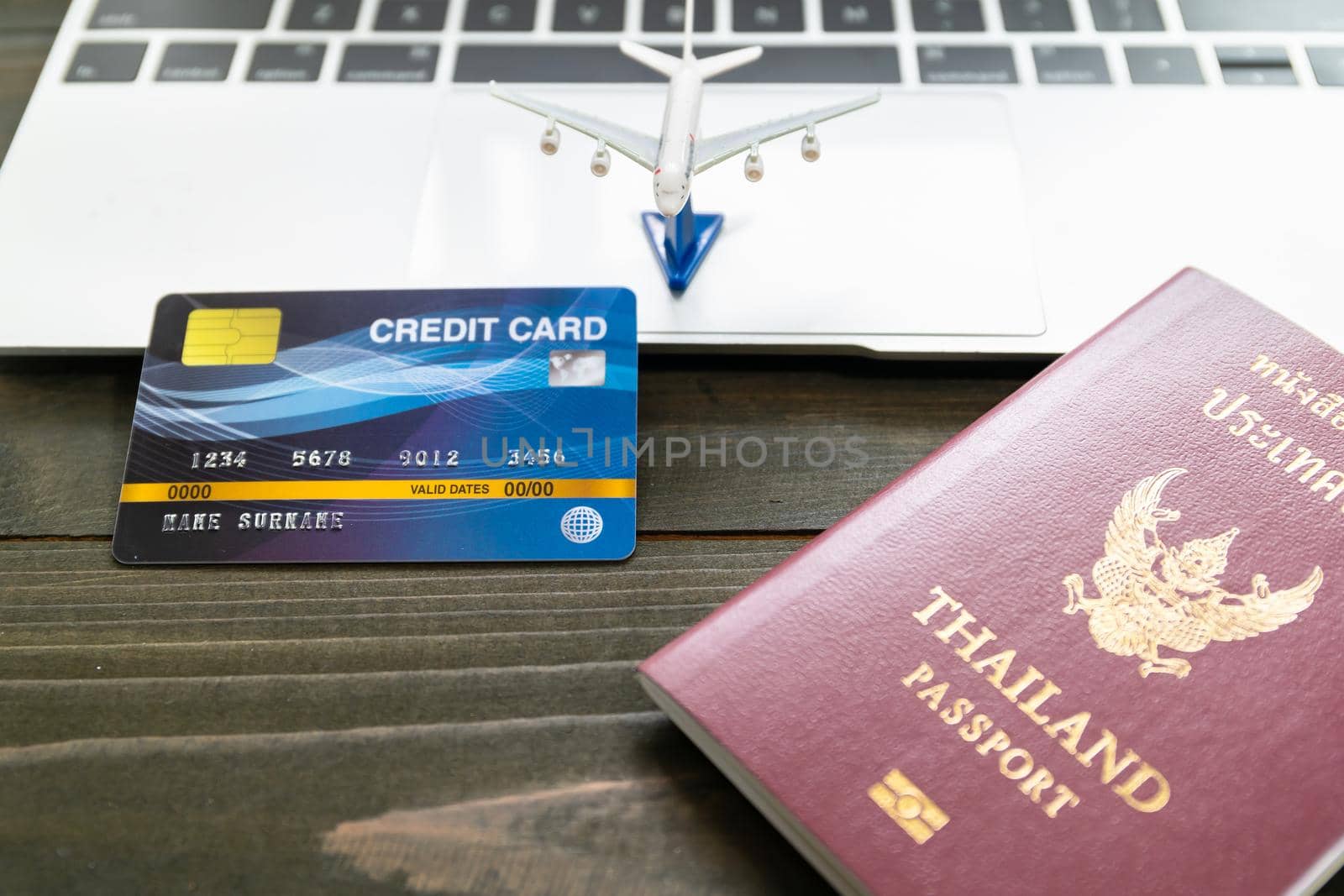 Passport with  credit card on laptop keyboard on a brown wooden background, Preparation for Traveling concept