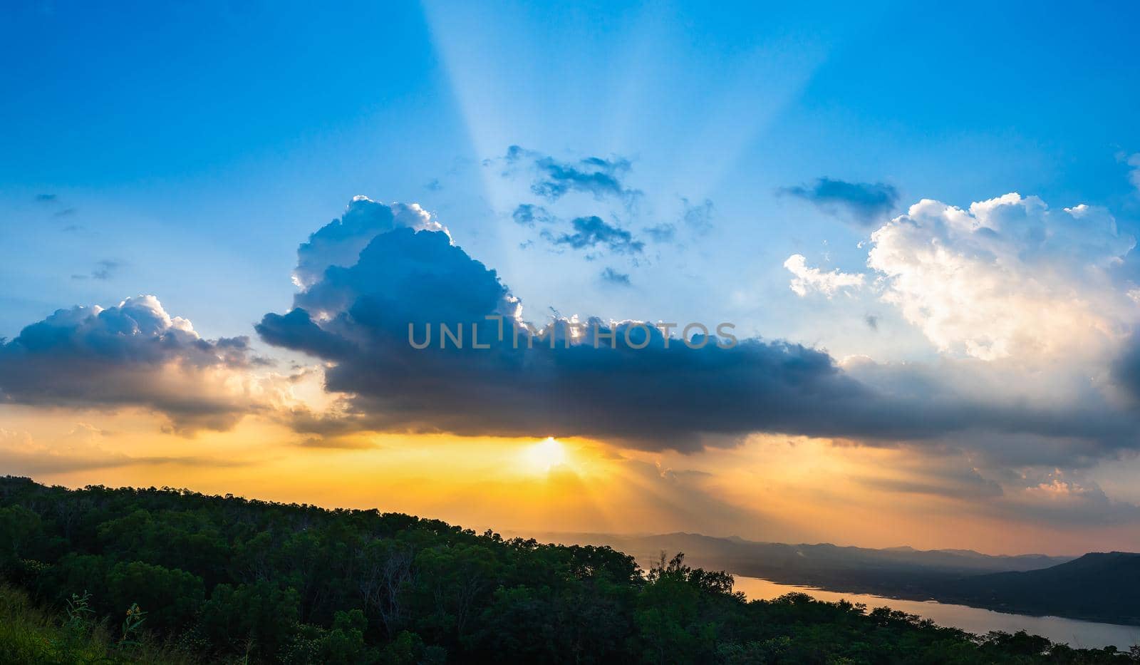 Sunset with ray light on clouds in a blue and orange sky in twilight time