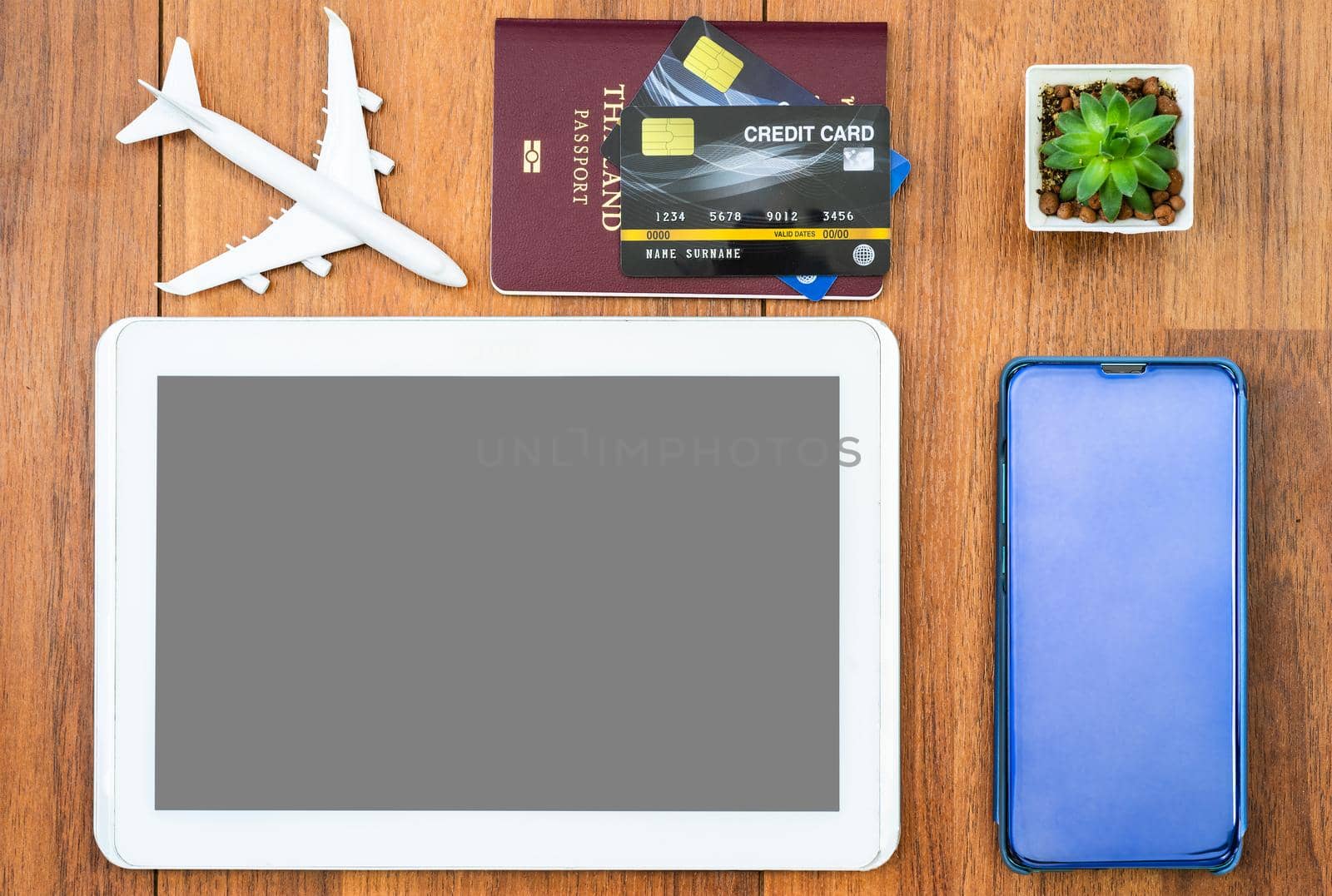 Top view Passport with credit card and smartphone and  digital tablet mock up on brown wooden desk background, Preparation for Traveling concept