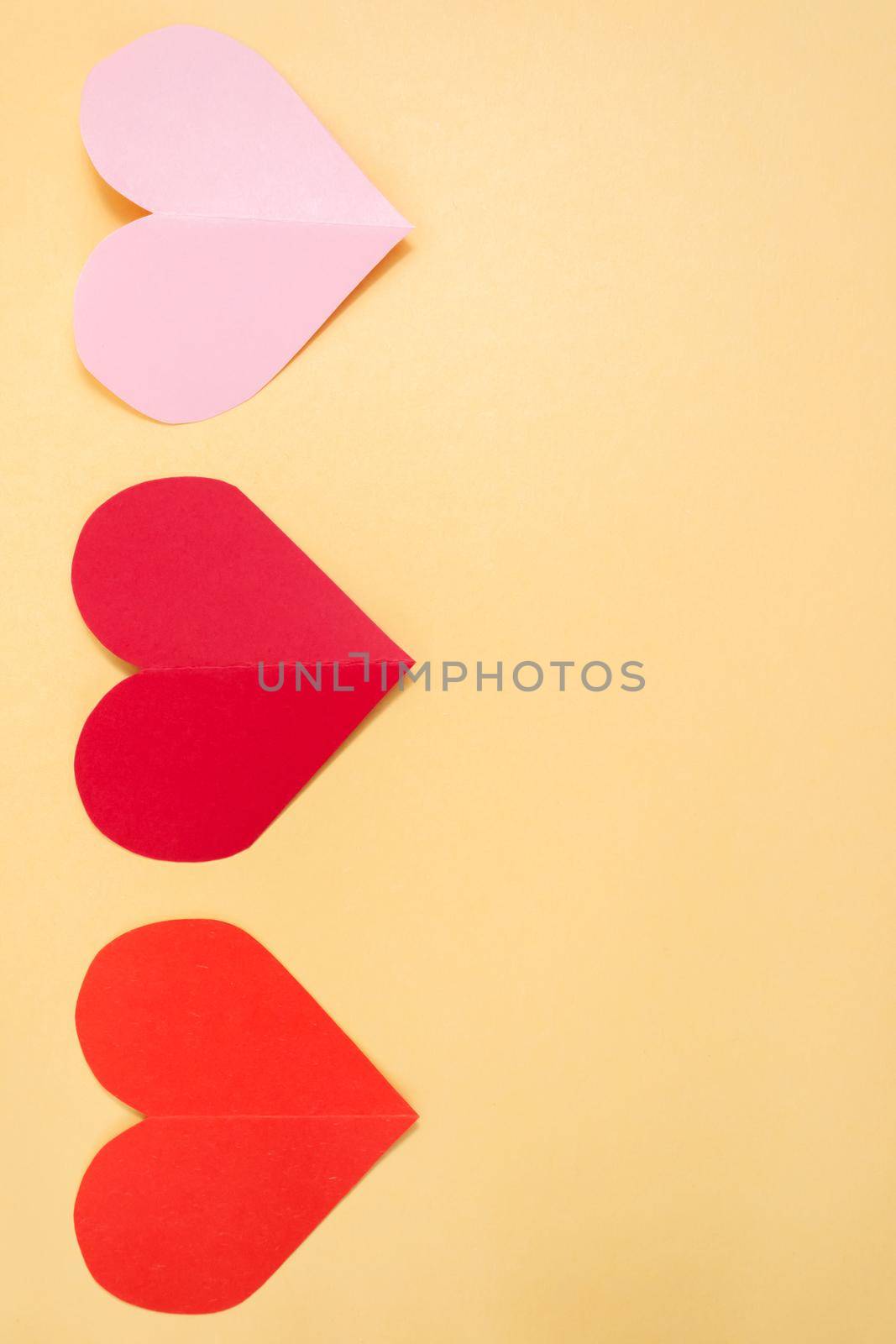 Valentine's Day background. Pink and red hearts on a pastel yellow background. Valentine's Day concept. Flat lay, top view, copy space