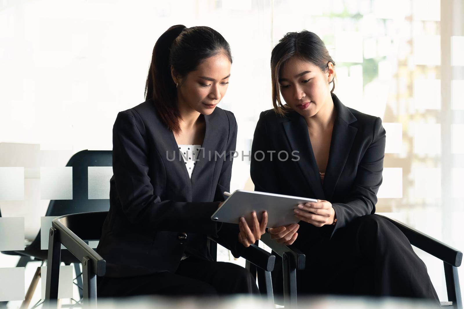 Two Businesswoman discuss to working with using tablet and for searching information stock market chart for trading to Make a profit. Planning and Investment concept by nateemee