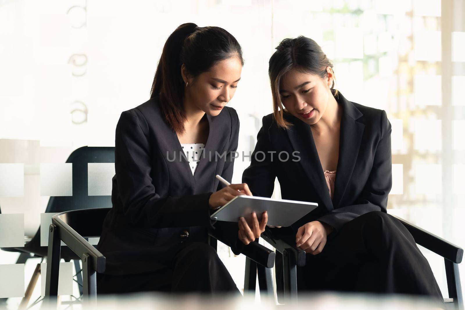Two Businesswoman discuss to working with using tablet and for searching information stock market chart for trading to Make a profit. Planning and Investment concept.