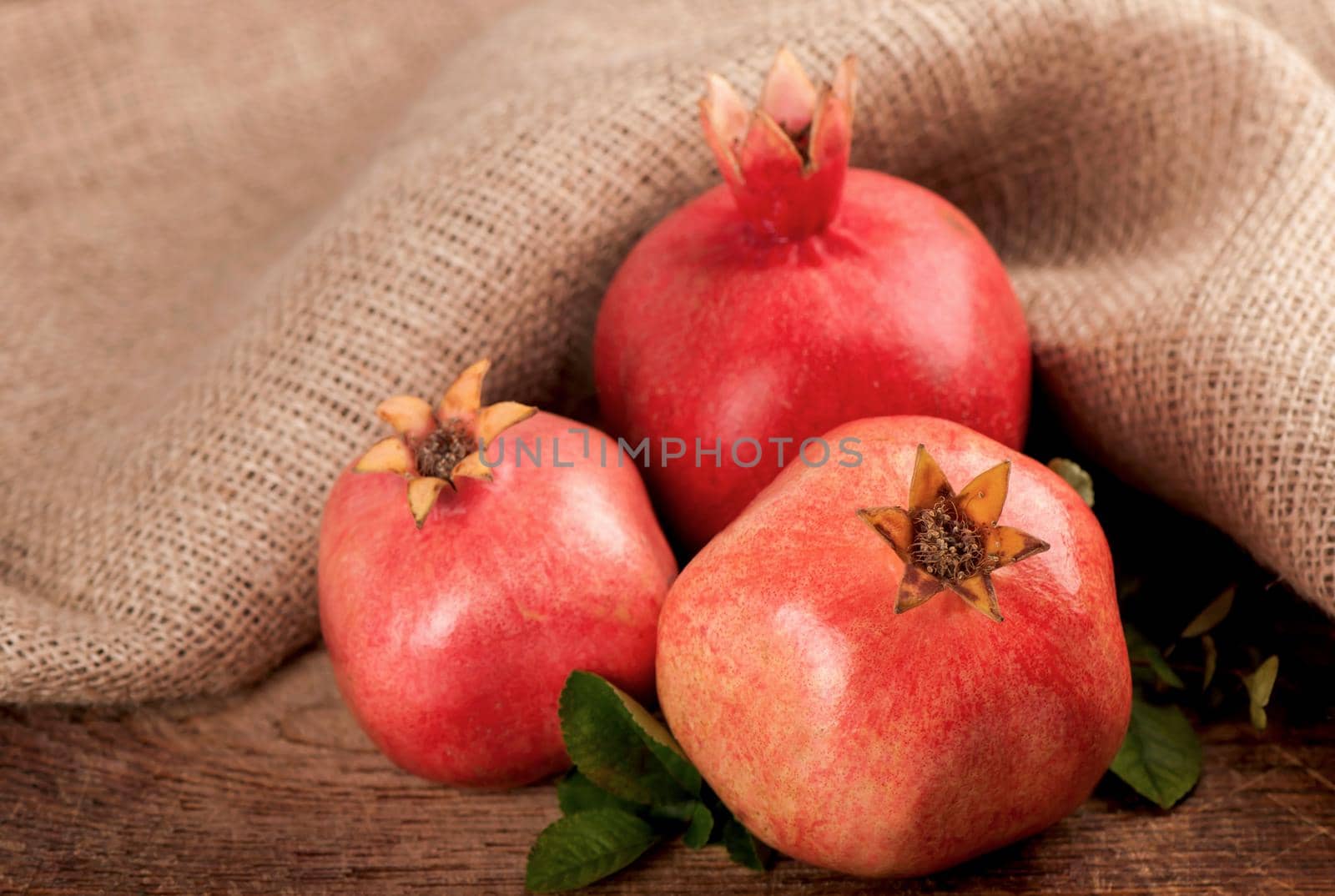 ripe pomegranate with leaves on a wooden board by aprilphoto