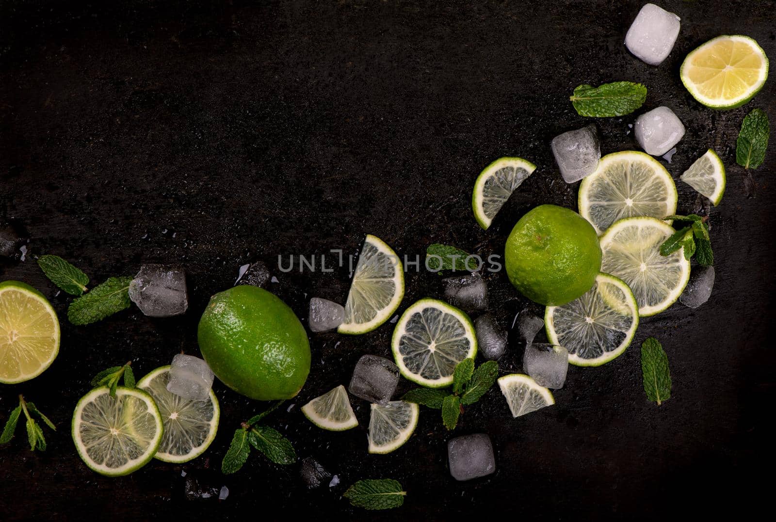 Fresh mint, lime and ice on a black background. Ingredient for mahito. by aprilphoto